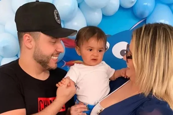Homem e mulher segurando bebê no colo entre eles