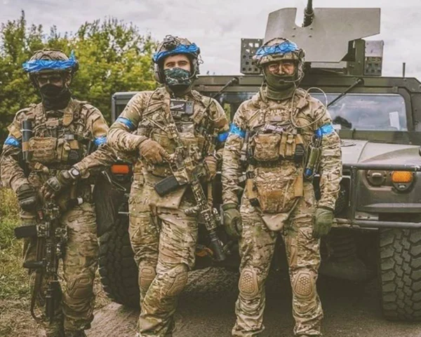Imagem colorida mostra três homens vestidos com roupas militares - Metrópoles