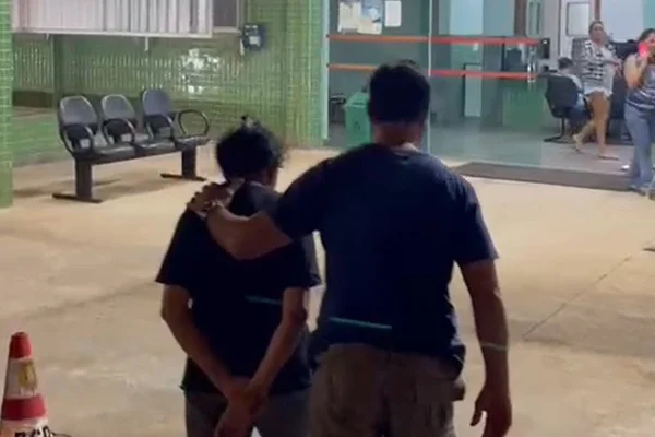 homem com mão em ombro de idosa algemada