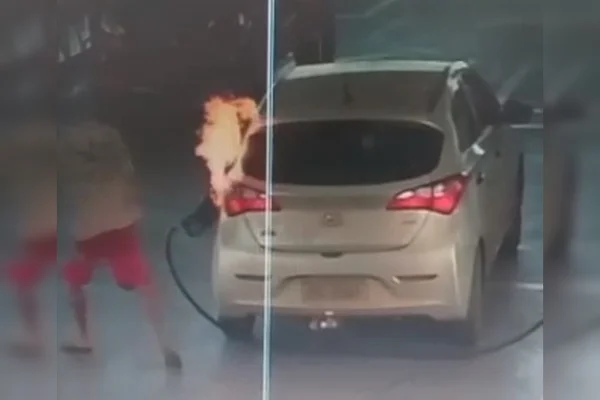 Carro pegando fogo enquanto abastece em posto e homem correndo à esquerda