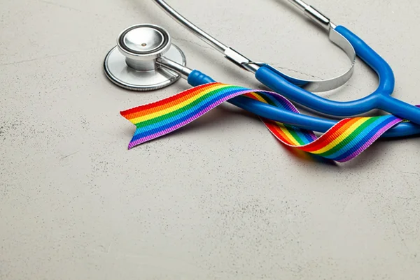 Imagem colorida de estetoscópio com fita da bandeira LGBT - Metrópoles