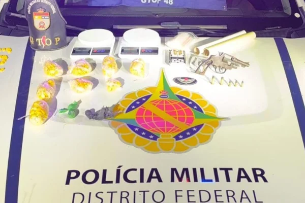 Foto colorida de capô de viatura da PMDF com drogas em armas