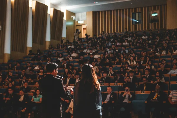 Fotografia colorida mostrando duas pessoas palestrando para auditório lotado - Metrópoles