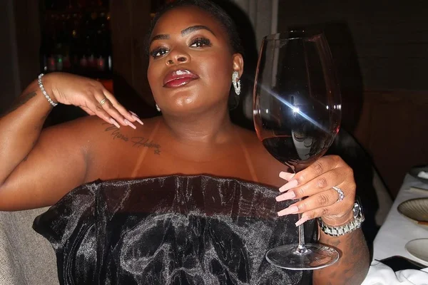 Jojo Todynho posa segurando uma taça de vinho e usando um look preto - Metrópoles
