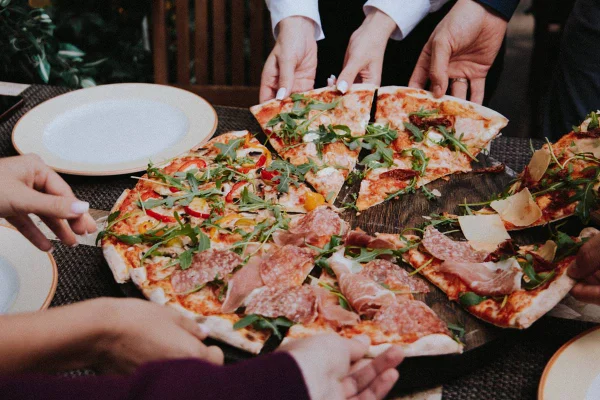 Pessoas pegando pedaços de pizza