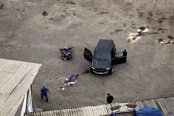 Imagem colorida, corpo de policial policial no chão da garagem - Metrópoles