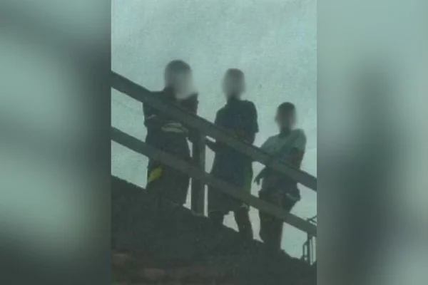 Imagem colorida mostra três jovens em um terraço olhando para baixo - Metrópoles