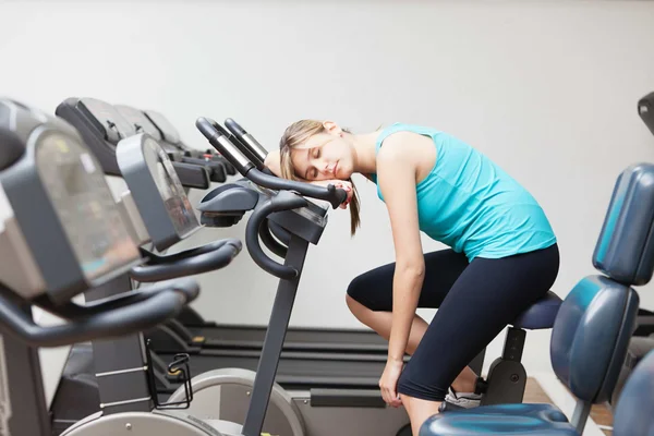 Foto mostra mulher descansando em bicicleta ergométirca sendentários exercício físico