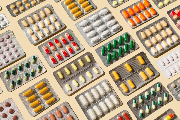 Diversas cartelas com comprimidos coloridos e cápsulas em fundo bege - Metrópoles