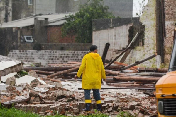 Foto colorida de homem junto de destroços de casa após forte temporal - Metrópoles