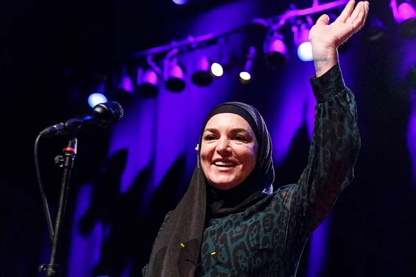 Foto colorida de Sinéad O'Connor sorrindo em show - Metrópoles
