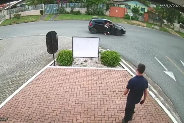 Imagem mostra agente da guarda municipal proximo a carro em que o marido agride a esposa - Metrópoles