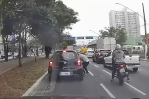 Imagem colorida de suspeito roubando celular de motorista parado no trânsito de SP. Metrópoles