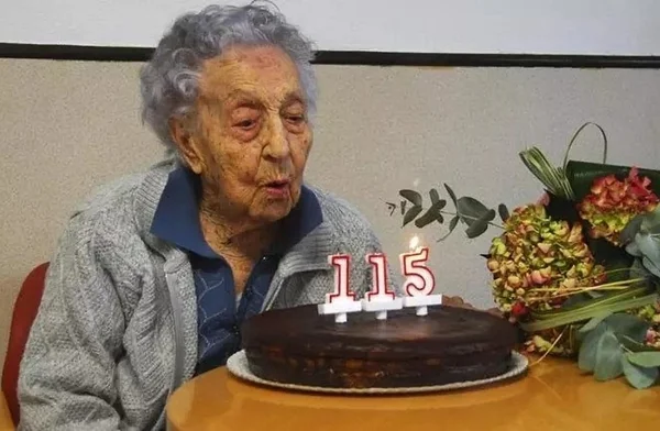 Foto colorida de uma idosa de 115 anos assoprando velas de aniversário - Metrópoles