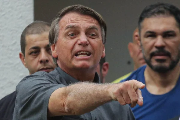 Bolsonaro ao lado de lutadores que declararam apoio à sua campanha em São Paulo. Ele aponta para frente, fazendo uma careta - Metrópoles
