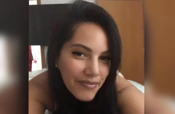 Foto colorida no estilo "selfie" de mulher deitada de bruços, olhando para a câmera; ela é parda e tem cabelos escuros