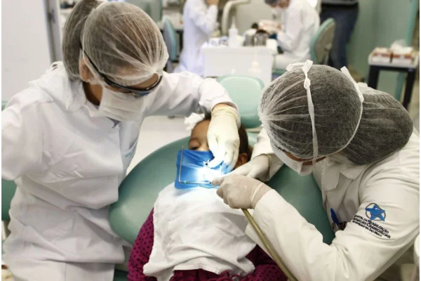 Imagem colorida mostra dentistas tratando paciente com doença nos dentes - Metrópoles