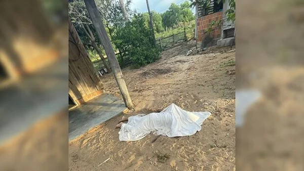 Imagem do cadáver da vítima, coberto com um pano branco, ao redor de uma área de fazenda - Metrópoles