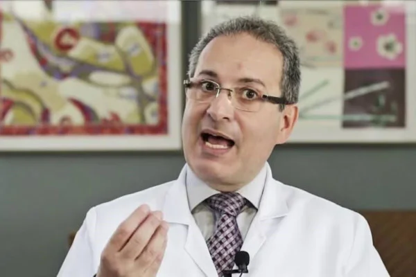 Imagem colorida de um homem branco em um jaleco de médico