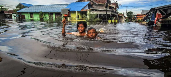 Imagem colorida mostra duas pessoas em alagamento por conta de aumento do nível do mar - Metrópoles