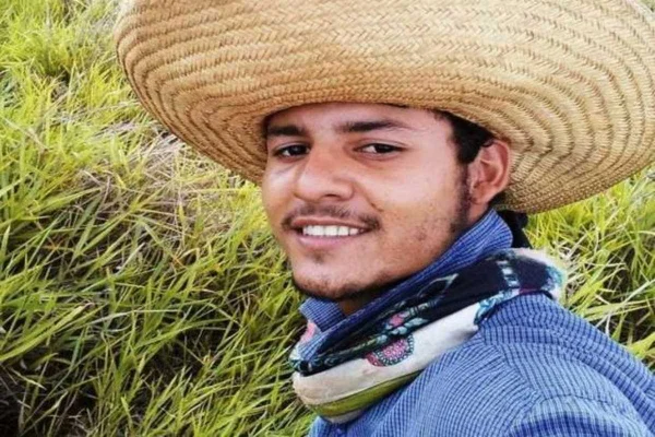 Homem em pé com chapéu de palha