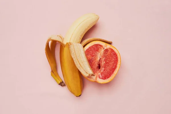 Banana e toranja lado a lado em fundo rosa - Metrópoles