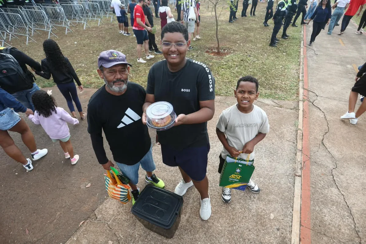 O avô levou os dois netos para o desfile. O mais velho aproveitou para vender pudins no evento O avô levou os dois netos para o desfile. O mais velho aproveitou para vender pudins no evento
