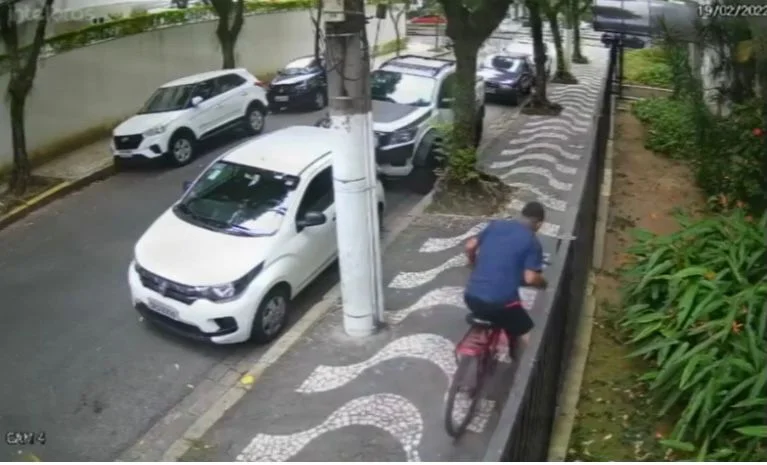 Um dos assaltantes se aproveita que ela se afasta e volta de bicicleta para pegar a bolsa dela Um dos assaltantes se aproveita que ela se afasta e volta de bicicleta para pegar a bolsa dela