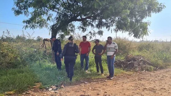 Foto colorida de policiais militares e investigadores da Polícia Civil na área em que o corpo foi encontrado