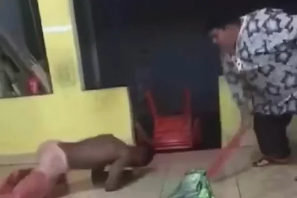 Homem segura um cabo de vassoura após bater em homem que está no chão