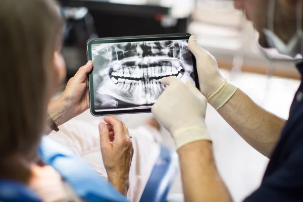 Imagem mostra dentistas discutindo e apontando para um raio X dos dentes - Metrópoles