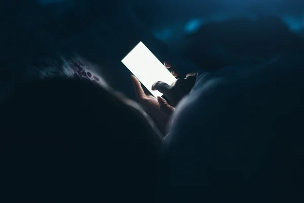 Imagem colorida de uma pessoa mexendo no celular de noite/ vídeo intimo - Metrópoles