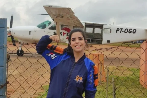 Imagem colorida de mulher na frente de um avião de pequeno porte. Metrópoles