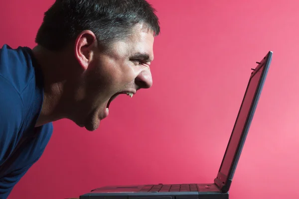 Imagem mostra um homem branco, de meia idade proferindo palavras de ódio em frente ao notebook - Metrópoles - suplemento agressividade