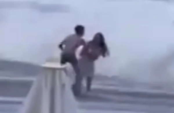 Imagem colorida de momentos antes de mulher ser arrastada pelo mar - Metrópoles