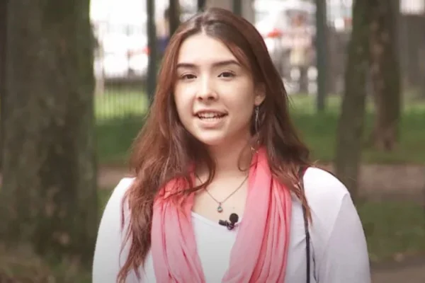 Foto de mulher branca com blusa branca e cachecol rosa - Metrópoles