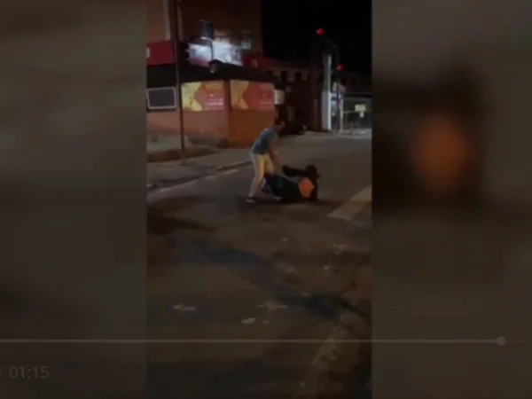 Foto colorida mostra mulher sendo agredida no meio da rua