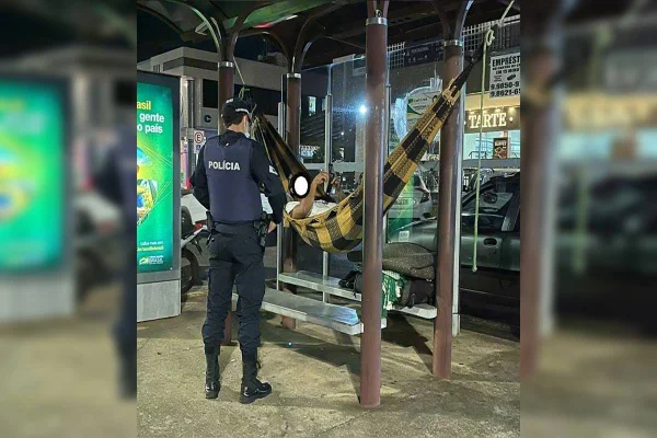 Homem dorme em rede em parada de ônibus