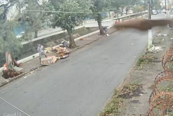 Imagem colorida de árvores em via e homens em situação de rua. Metrópoles