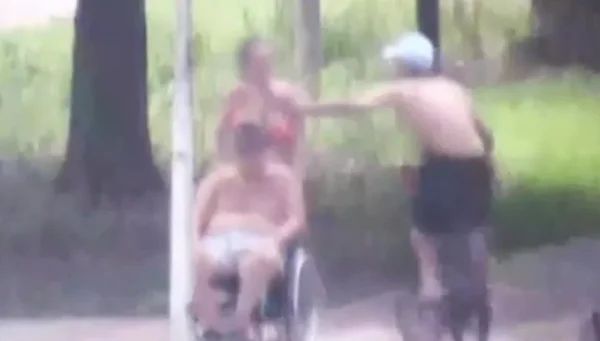Imagem colorida mostra ciclista roubando corrente de mulher que anda pela orla de Santos com um cadeirante - Metrópoles