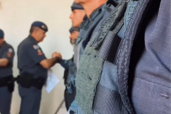 PM fardado dá a mão para outro que compõe fila, na qual há seis policiais, lado a lado - Metrópoles