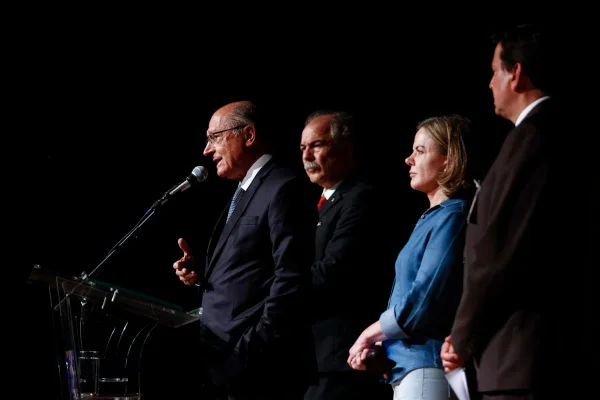 Foto colorida de Geraldo Alckmin e equipe do governo de transição num fundo escuro