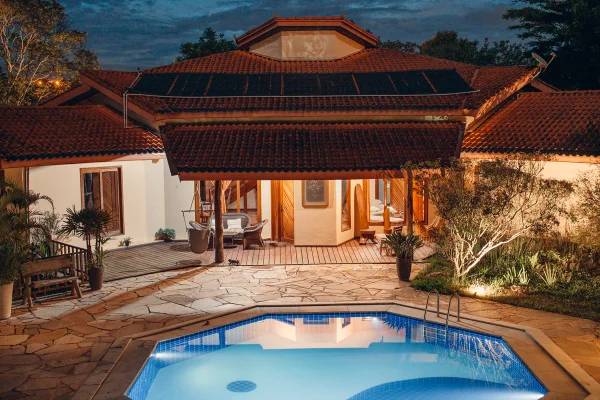Foto colorida. Imagem áerea mostra a casa da Vila Baru e a piscina ao anoitecer - Metrópoles