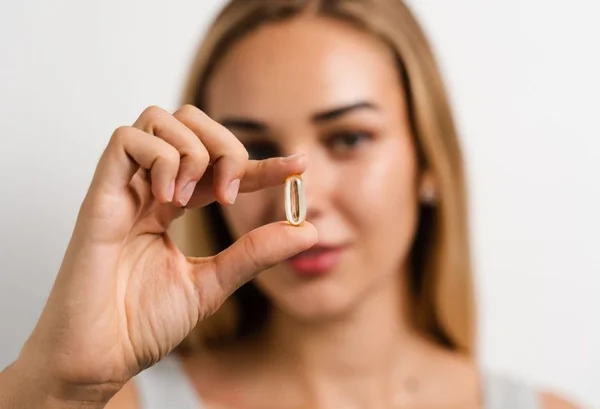 Mulher segurando uma capsula de omega 3