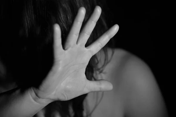 Imagem preta e branca com uma pessoa com a mão no rosto denunciando abuso sexual