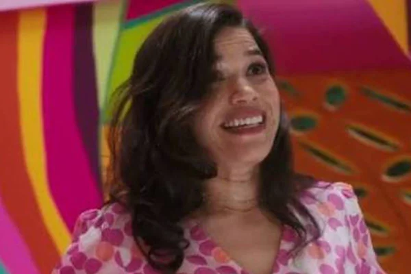 Foto de uma mulher branca, de cabelo preto e médio, sorrindo. Ela usa vestido rosa com branco e o fundo da imagem é colorido - Metrópoles