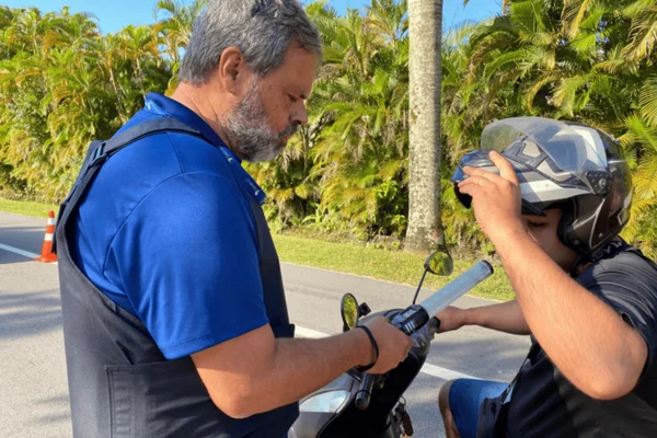 Imagem colorida de um motorista de moto sendo abordado por um policial durante blitz da lei seca - Metrópoles