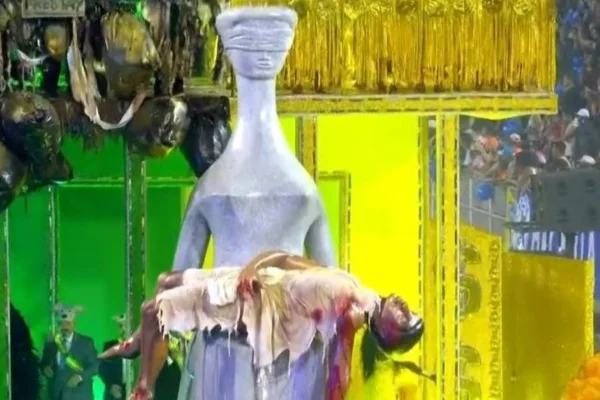 Imagem colorida de alegoria com a estátua Artemis segurando uma criança morta nos braços. Metrópoles