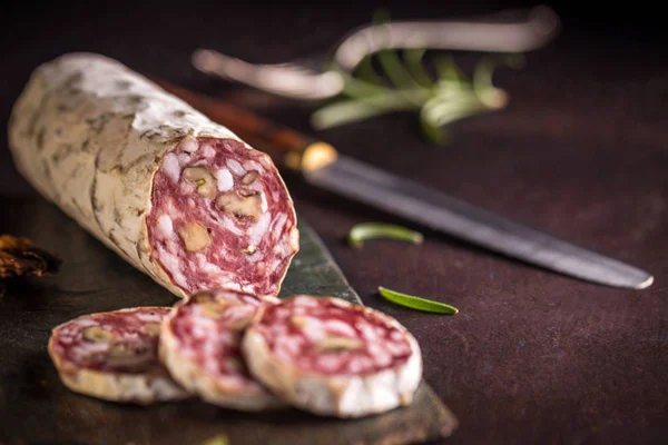 Salame com superfísice com casca branca que sinaliza formação de mofo no alimento que está em cima da mesa ao lado de uma faca