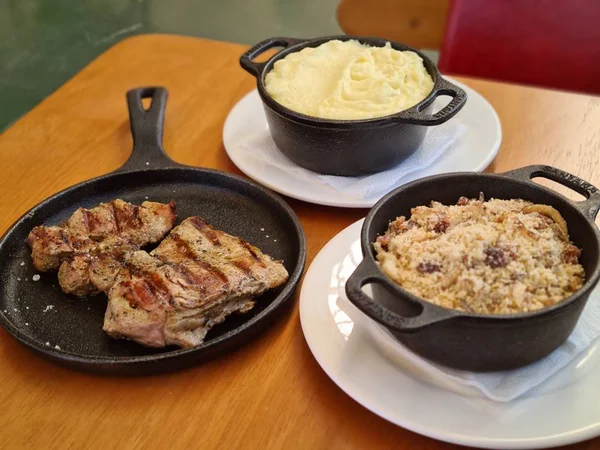 Três recipientes pretos com comidas diversas